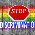 STOP sign and discrimination on top of LGBT flag painted on background