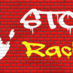 stop racism graffiti written over bricks and handprint