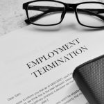 Employment Termination letter with pen,eye glasses and book.