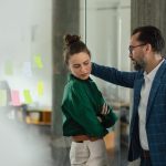 Mature man abusing his younger colleague, concept of harassment at workplace.