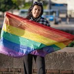 Transgender woman holding lgbt flag looking at the camera